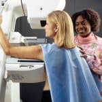 A woman gets a mammogram with assistance from a healthcare professional in a colorful blouse, finding comfort in practical tips to cope with scanxiety.