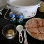A crock pot full of food and a can of soda.
