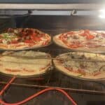 A pizza oven with several homemade pizzas in it.