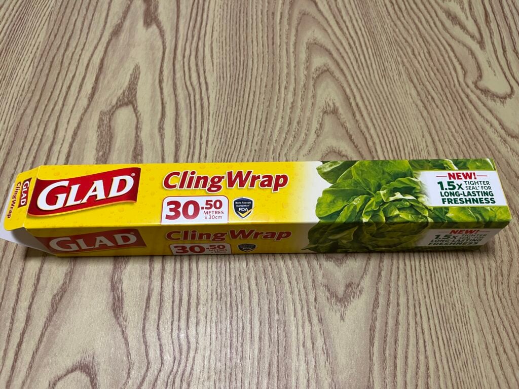 A box of Glad Cling Wrap with 30 meters length, featuring a green leafy vegetable image and a label highlighting 1.5x longer-lasting freshness.