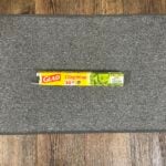 A box of Glad Cling Wrap is placed on a gray mat, with a wooden floor in the background.