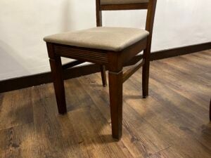 Dark wood dining chair with a beige upholstered seat.