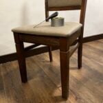 A pair of scissors and a roll of duct tape sitting on a wooden chair.