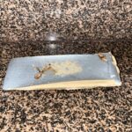 A strip of adhesive insect trap on a granite countertop, containing two cockroaches and a small pile of bait.